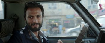 Movie still from “A Hero” (2021), directed by Asghar Farhadi – A man sitting in the back seat of a car; Close Up shot, Over the shoulder angle