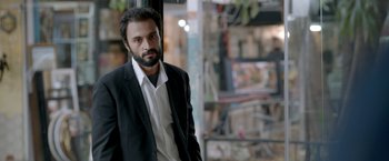 Movie still from “A Hero” (2021), directed by Asghar Farhadi – A man in a suit and tie standing in front of a store window; Close Up shot, Low angle