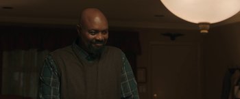 Movie still from “A Journal for Jordan” (2021), directed by Denzel Washington – A man in a plaid shirt is smiling at the camera; Medium shot, Over the shoulder angle
