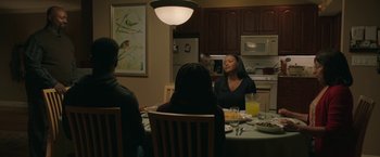 Movie still from “A Journal for Jordan” (2021), directed by Denzel Washington – A group of people sitting around a table with food on top of it; Medium shot, Over the shoulder angle
