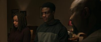 Movie still from “A Journal for Jordan” (2021), directed by Denzel Washington – A man in a black and gray hoodie is looking at the camera; Medium shot, Over the shoulder angle