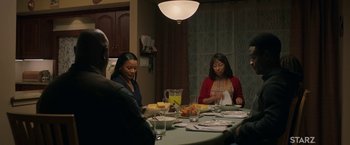 Movie still from “A Journal for Jordan” (2021), directed by Denzel Washington – A group of people sitting around a table eating food; Medium shot, Over the shoulder angle