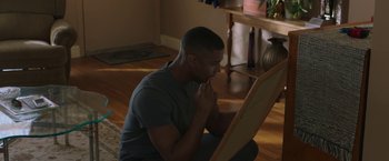Movie still from “A Journal for Jordan” (2021), directed by Denzel Washington – A man sitting on the floor in front of an easel; Medium shot, Over the shoulder angle