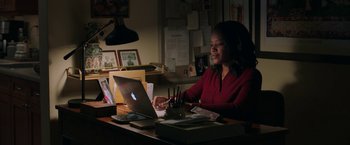 Movie still from “A Journal for Jordan” (2021), directed by Denzel Washington – A woman sitting at a desk using a laptop computer; Medium shot, High angle