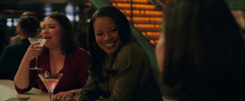 Movie still from “A Journal for Jordan” (2021), directed by Denzel Washington – A woman smiles while sitting at a table in a restaurant; Medium shot, Over the shoulder angle