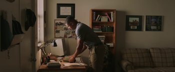 Movie still from “A Journal for Jordan” (2021), directed by Denzel Washington – A man standing in front of a computer desk; Medium shot, Low angle