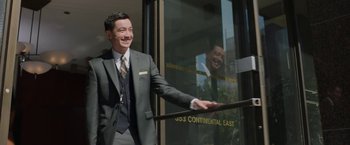 Movie still from “A Journal for Jordan” (2021), directed by Denzel Washington – A man wearing a suit and tie standing in front of a building; Medium shot, Low angle