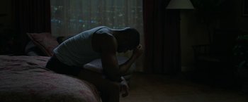 Movie still from “A Journal for Jordan” (2021), directed by Denzel Washington – A man sitting on the edge of a bed in the dark; Medium shot, High angle