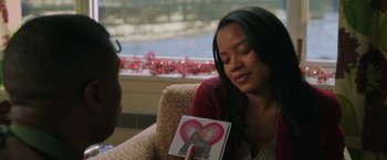 Movie still from “A Journal for Jordan” (2021), directed by Denzel Washington – A woman sitting in a chair holding up a picture; Close Up shot, Over the shoulder angle