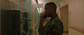 Movie still from “A Journal for Jordan” (2021), directed by Denzel Washington – A man talking on a phone while wearing a camouflage uniform; Medium shot, Over the shoulder angle