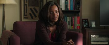 Movie still from “A Journal for Jordan” (2021), directed by Denzel Washington – A woman sitting on a couch in a room; Medium shot, Over the shoulder angle