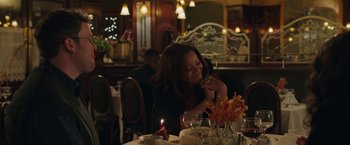 Movie still from “A Journal for Jordan” (2021), directed by Denzel Washington – A woman sitting at a table with a candle in her mouth; Medium shot, Over the shoulder angle