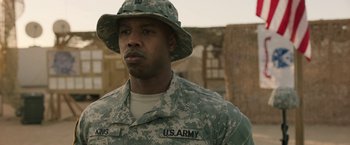 Movie still from “A Journal for Jordan” (2021), directed by Denzel Washington – A man in fatigues is wearing a hat; Close Up shot, Over the shoulder angle