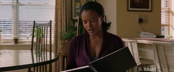 Movie still from “A Journal for Jordan” (2021), directed by Denzel Washington – A woman sitting at a table looking at an open book; Medium shot, Over the shoulder angle