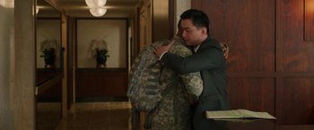 Movie still from “A Journal for Jordan” (2021), directed by Denzel Washington – A man in a business suit hugging a soldier in fatigues; Medium shot, Over the shoulder angle