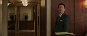Movie still from “A Journal for Jordan” (2021), directed by Denzel Washington – A man in a suit standing in a hotel hallway; Medium shot, Over the shoulder angle