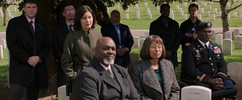 Movie still from “A Journal for Jordan” (2021), directed by Denzel Washington – A group of people sitting in front of a grave; Medium shot, High angle