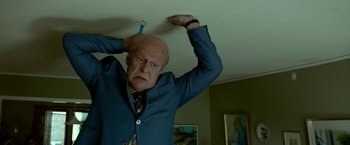 Movie still from “A Man Called Ove” (2015), directed by Hannes Holm – An older man in a suit and tie holding onto a rope; Medium shot, Low angle