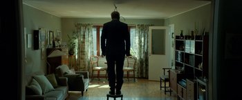 Movie still from “A Man Called Ove” (2015), directed by Hannes Holm – A man standing on top of a stool in a living room; Wide shot, Low angle