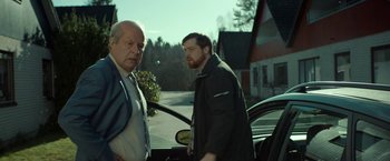 Movie still from “A Man Called Ove” (2015), directed by Hannes Holm – Two men standing next to each other in front of a car; Medium shot, Over the shoulder angle