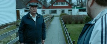 Movie still from “A Man Called Ove” (2015), directed by Hannes Holm – An older man standing in front of a red house; Medium shot, Over the shoulder angle