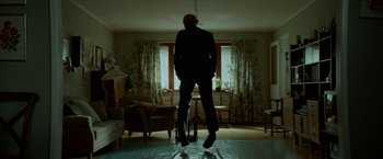 Movie still from “A Man Called Ove” (2015), directed by Hannes Holm – A man standing in a living room with his head in the air; Wide shot, Low angle