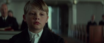 Movie still from “A Man Called Ove” (2015), directed by Hannes Holm – A young boy in a suit and tie looking at the camera; Close Up shot, Low angle