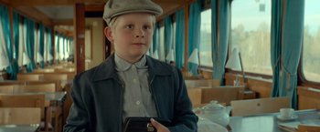 Movie still from “A Man Called Ove” (2015), directed by Hannes Holm – A young boy in a hat and jacket holding a purse; Close Up shot, Low angle