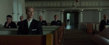 Movie still from “A Man Called Ove” (2015), directed by Hannes Holm – A group of men in suits standing in front of pews; Medium shot, Low angle
