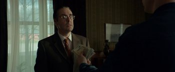 Movie still from “A Man Called Ove” (2015), directed by Hannes Holm – A man in a brown suit is holding money in his hand; Medium shot, Over the shoulder angle