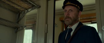 Movie still from “A Man Called Ove” (2015), directed by Hannes Holm – A man with a beard wearing a hat and a tie; Medium shot, Low angle