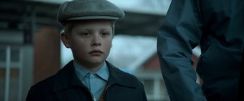 Movie still from “A Man Called Ove” (2015), directed by Hannes Holm – A young boy wearing a hat and a jacket; Close Up shot, Low angle