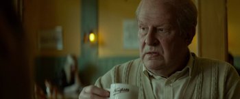 Movie still from “A Man Called Ove” (2015), directed by Hannes Holm – An older man holding a coffee cup in his hand; Close Up shot, Over the shoulder angle