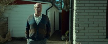 Movie still from “A Man Called Ove” (2015), directed by Hannes Holm – An older man standing in front of a building; Medium shot, Low angle