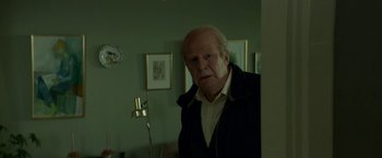 Movie still from “A Man Called Ove” (2015), directed by Hannes Holm – An older man standing in a room with a lamp; Medium shot, Over the shoulder angle