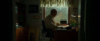 Movie still from “A Man Called Ove” (2015), directed by Hannes Holm – An older man sitting at a desk in front of a window; Medium shot, Low angle