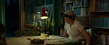 Movie still from “A Man Called Ove” (2015), directed by Hannes Holm – A woman sitting at a table with papers and a glass of juice; Medium shot, Over the shoulder angle