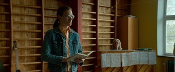 Movie still from “A Man Called Ove” (2015), directed by Hannes Holm – A man in a denim jacket holding an open book in his hands; Medium shot, Over the shoulder angle