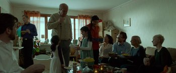 Movie still from “A Man Called Ove” (2015), directed by Hannes Holm – A group of people sitting around a table with food on it; Medium shot, Over the shoulder angle