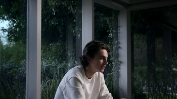 Movie still from “A Man Named Scott” (2021), directed by Robert Alexander – A man sitting in front of a window with trees in the background; Medium shot, Over the shoulder angle