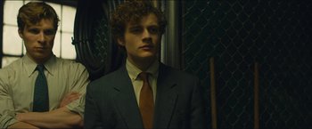 Movie still from “A Most Violent Year” (2014), directed by J.C. Chandor – A man in a suit and tie standing in front of a chain link fence; Close Up shot, Low angle