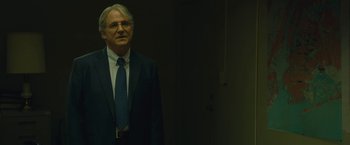 Movie still from “A Most Violent Year” (2014), directed by J.C. Chandor – An older man wearing a suit and tie in front of a wall; Medium shot, Over the shoulder angle