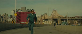 Movie still from “A Most Violent Year” (2014), directed by J.C. Chandor – A man running across a street near a bridge; Wide shot, Low angle
