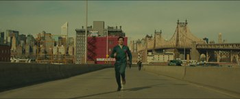 Movie still from “A Most Violent Year” (2014), directed by J.C. Chandor – A man running down a street with a sign on his chest; Extreme Wide shot, Low angle