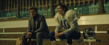 Movie still from “A Most Violent Year” (2014), directed by J.C. Chandor – Two young men sitting on a bench in front of a building; Medium shot, Over the shoulder angle