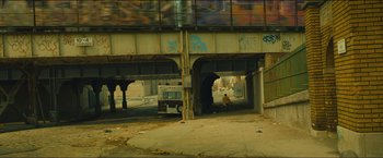 Movie still from “A Most Violent Year” (2014), directed by J.C. Chandor – A person sitting under a bridge in a city; Extreme Wide shot, High angle