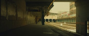 Movie still from “A Most Violent Year” (2014), directed by J.C. Chandor – A person walking on a train platform next to train tracks; Extreme Wide shot, Low angle