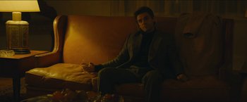 Movie still from “A Most Violent Year” (2014), directed by J.C. Chandor – A man sitting on top of a brown leather couch; Medium shot, Low angle