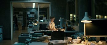 Movie still from “A Most Wanted Man” (2014), directed by Anton Corbijn – A woman sitting at a desk in front of a computer; Wide shot, High angle