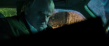 Movie still from “A Most Wanted Man” (2014), directed by Anton Corbijn – A man sitting in the back seat of a car; Close Up shot, Over the shoulder angle